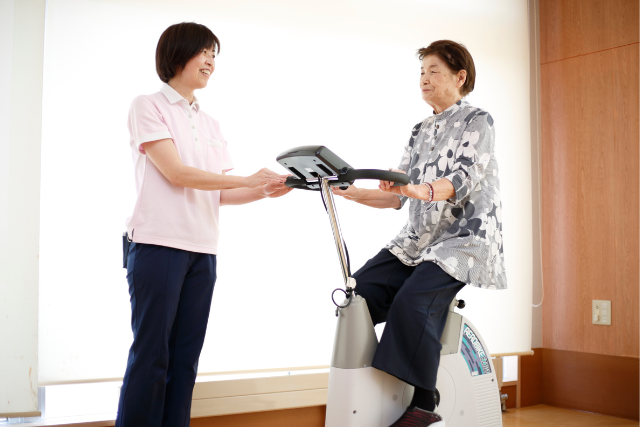 運動器具を使う利用者様を見守る職員の様子