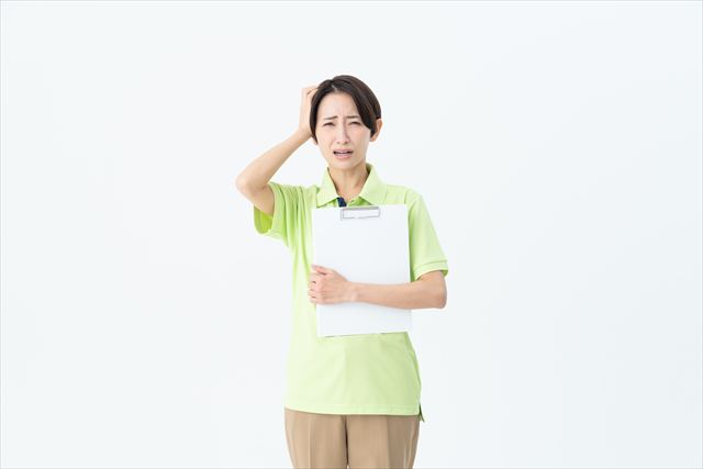 困った様子で頭を抱える介護職員