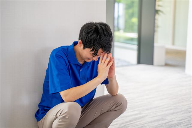 しゃがみ込んで考える男性介護職員